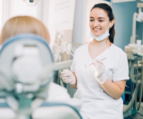 Junge Zahnarzthelferin behandelt Patient