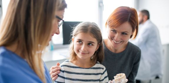 Zahnärztin erklärt Mädchen und Mutter etwas Anhand eines Kiefermodells