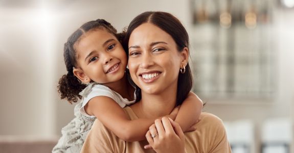 Tochter auf der Couch umarmt Mutter von hinten