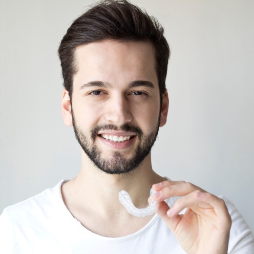 Mann hält durchsichtige Zahnspange