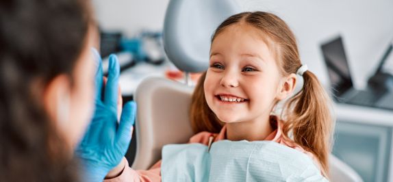 Kleines Mädchen mit Stofftier gibt Zahnarzt high five