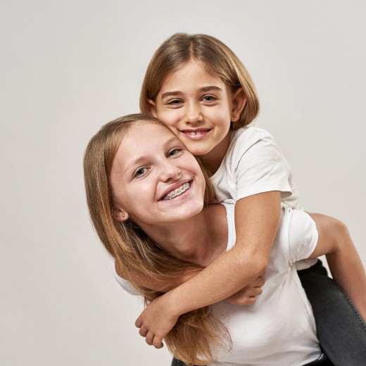 Schwestern spielen lachend Huckepack