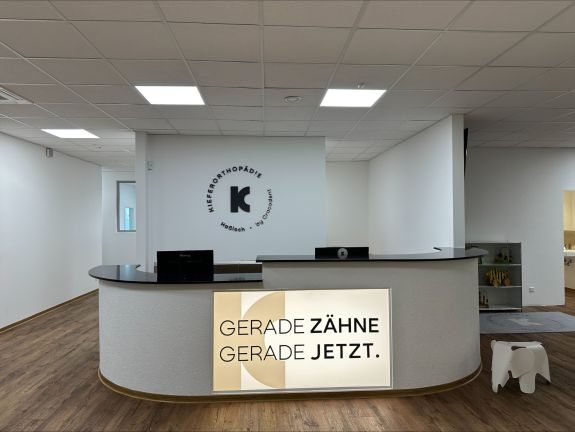 Anmeldungsthresen mit Leuchtschild &quot;Gerade Zähne, Gerade jetzt&quot;